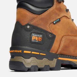 Close up of Timberland Boondock non-safety 6-inch waterproof men's work boot in tan showing soft toe tag with a blank background.