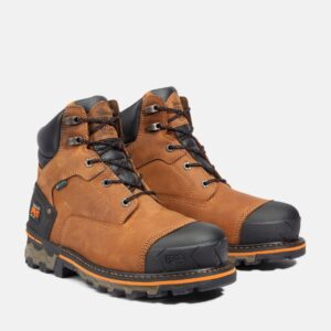 A turned pair of Timberland Boondock soft toe 6-inch waterproof men's work boots in tan with a blank background.