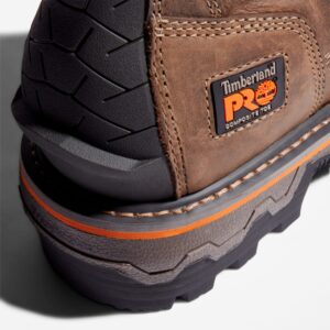 Close up of Timberland Boondock HD safety toe men's logger work boot in brown showing composite toe tag with a blank background.