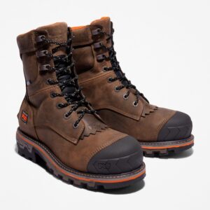 A turned pair of Timberland Boondock HD composite toe men's logger work boots in brown with a blank background.