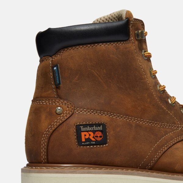 Close up of Timberland Gridworks safety toe men's 6-inch work boot in light brown showing alloy toe and waterproof tag with a blank background.