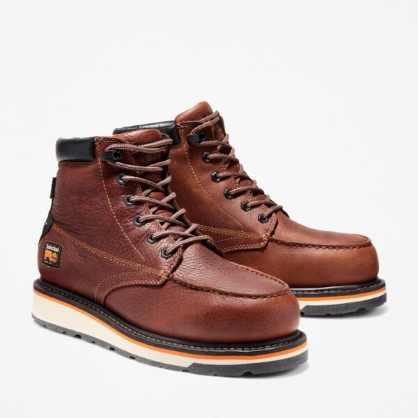 A turned pair of Timberland Gridworks alloy toe waterproof men's 6-inch work boots in brown with a blank background.