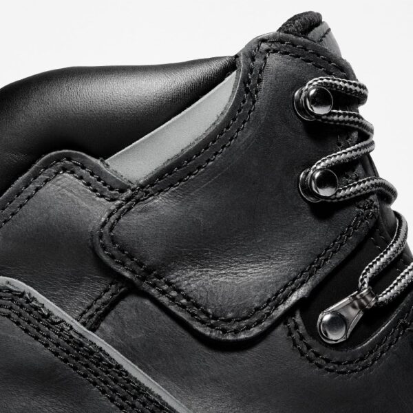 Close up of Timberland Pit Boss steel toe 6-inch men's work boot in black showing speed hooks and laces with a blank background.