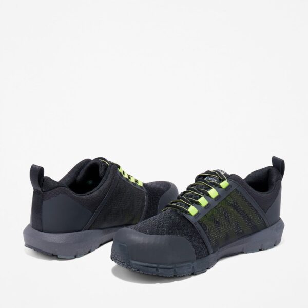 Offset pair of Timberland Radius composite toe low top men's work sneakers in black and green with a blank background.