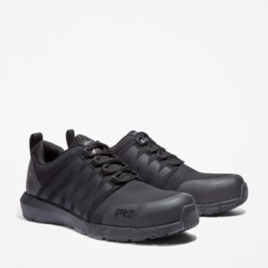 A turned pair of Timberland Radius composite toe low top men's work sneakers in black with a blank background.