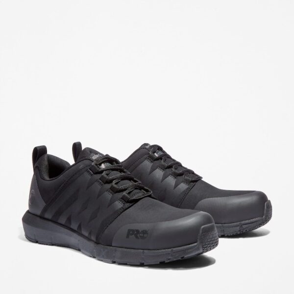 A turned pair of Timberland Radius composite toe low top men's work sneakers in black with a blank background.