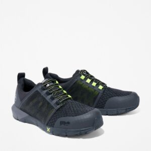 A turned pair of Timberland Radius composite toe low top men's work sneakers in black and green with a blank background.