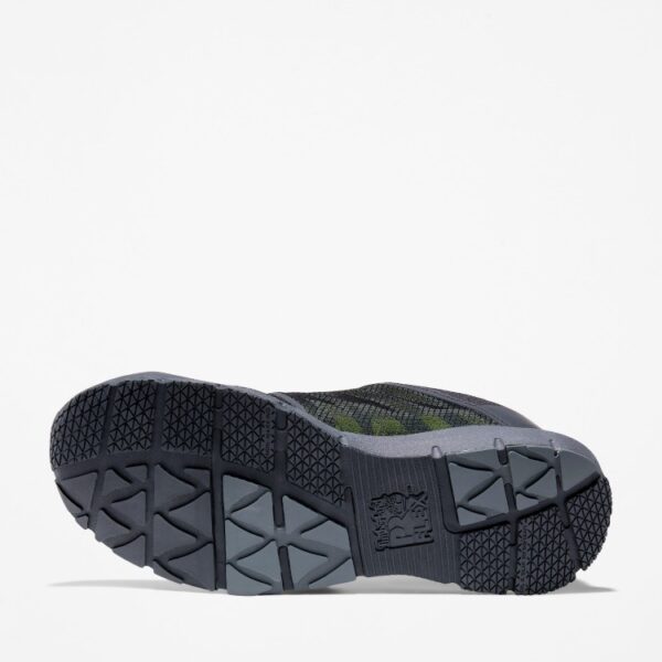 The sole of the right boot on a Timberland Radius composite toe men's low top work sneakers in black and green with a blank background.