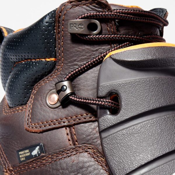 Close up of Timberland PRO Endurance Met Guard steel toe 6-inch men's work boot in brown showing puncture resistant sole tag with a blank background.