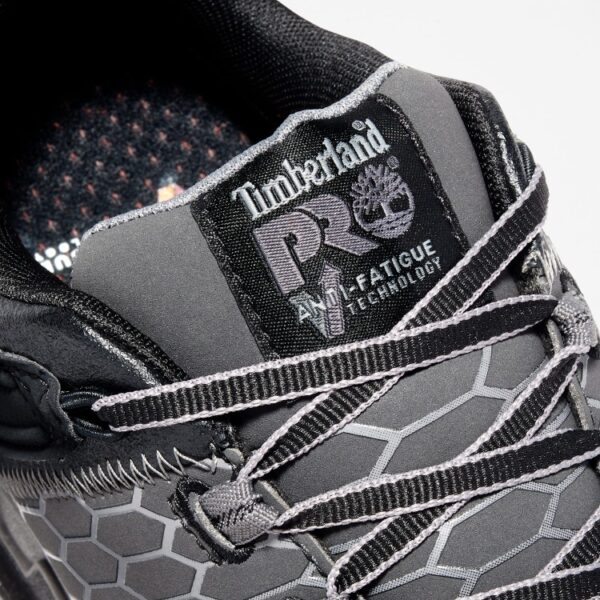 Close up of Timberland PRO Powertrain Sport alloy toe men's work sneakers in gray and black showing anti-fatigue technology tag with a blank background.