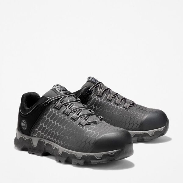 A turned pair of Timberland PRO Powertrain Sport alloy toe men's work sneakers in gray and black with a blank background.