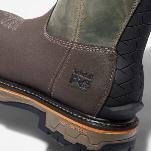 Close up of Timberland True Grit safety toe waterproof men's pull-on work boot in brown and green showing composite toe stamp and anti-fatigue marking with a blank background.