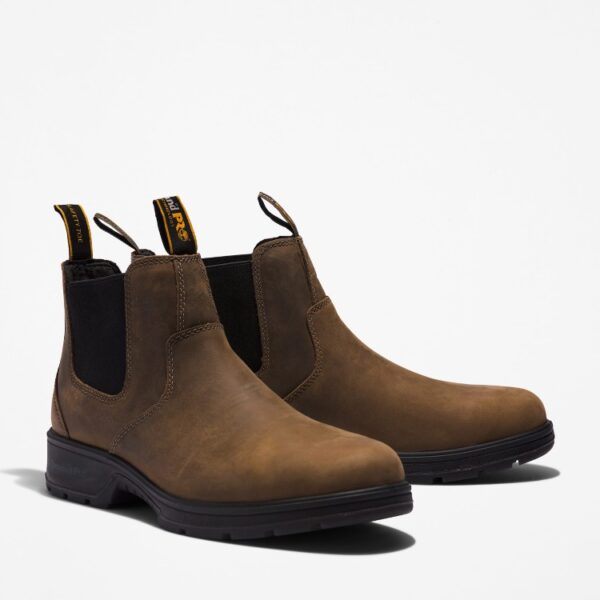 A turned pair of Timberland Nashoba Casual composite toe men's Chelsea work boots in brown with a blank background.