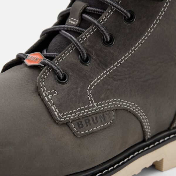 A closeup image of the left boot on a Brunt Grey Sullivan Limited Edition composite toe men's 6-inch work boot showing brand patch and insignia with a blank background.