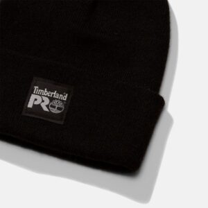 A close up look at the Timberland Watch Cap in black with a focus on the Timberland PRO tag on a blank background.