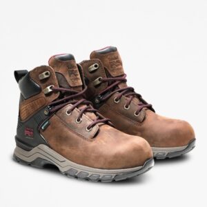 A turned pair of Timberland Hypercharge composite toe waterproof women's logger work boots in brown with a blank background.