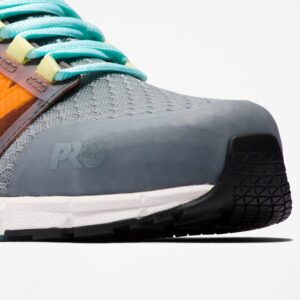 Close up of Timberland Radius composite toe women's work sneakers in gray, orange, black, and light blue showing Timberland PRO stamp with a blank background.