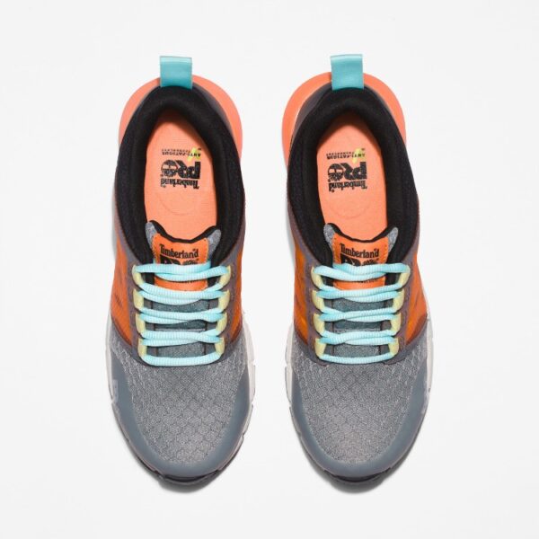 Overhead look at a pair of Timberland Radius composite toe women's work sneakers in gray, orange, black, and light blue on a blank background.