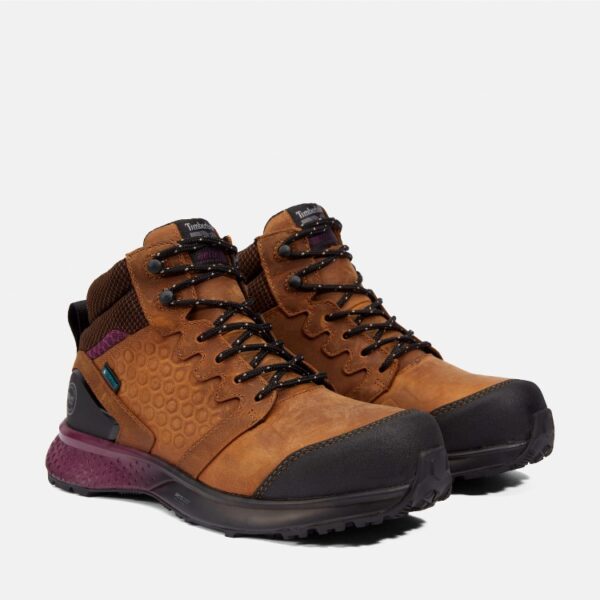 A turned pair of Timberland Reaxion composite toe waterproof women's work sneakers in tan and purple with a blank background.