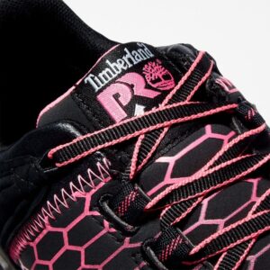 Close up of Timberland PRO Powertrain Sport alloy toe women's work sneakers in black and pink showing anti-fatigue technology tag with a blank background.