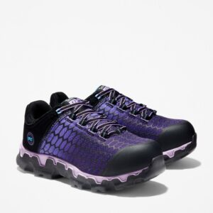 A turned pair of Timberland PRO Powertrain Sport alloy toe women's work sneakers in purple and black with a blank background.
