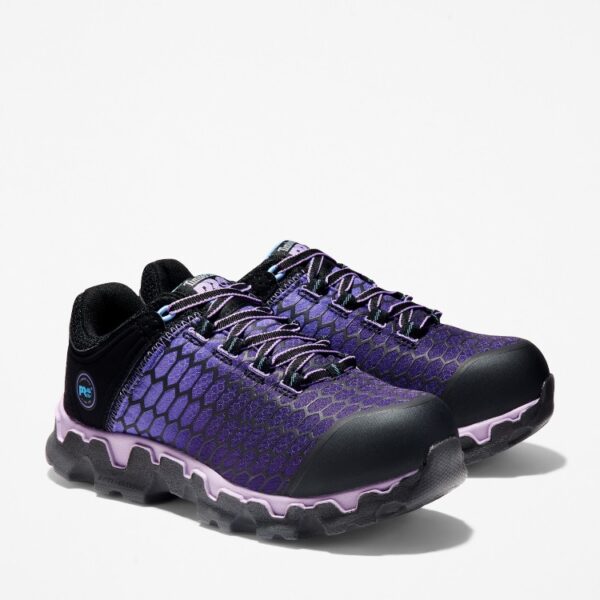 A turned pair of Timberland PRO Powertrain Sport alloy toe women's work sneakers in purple and black with a blank background.