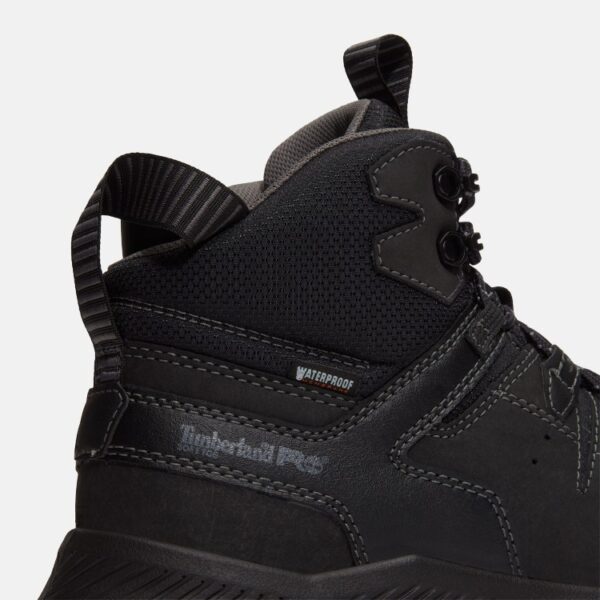 Close up of Timberland Tempe non-safety toe men's work boots in black showing soft toe stamp and waterproof tag with a blank background.