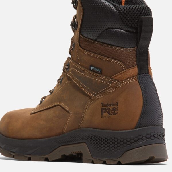 Close up of Timberland TiTAN EV non-safety toe men's 8-inch work boot in brown showing soft toe stamp and waterproof tag with a blank background.