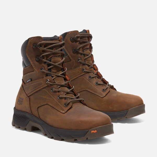 A turned pair of Timberland TiTAN EV soft toe waterproof men's 8-inch work boots in brown with a blank background.