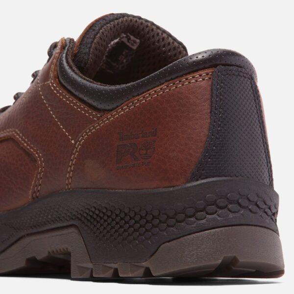Close up of Timberland TiTAN EV safety toe men's Oxford work shoe in brown showing composite toe stamp with a blank background.