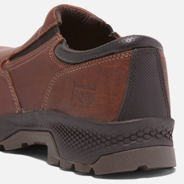 Close up of Timberland TiTAN EV safety toe men's slip-on work shoe in brown showing composite toe stamp with a blank background.