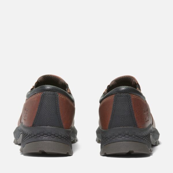 A look at the heels of a pair of Timberland TiTAN EV composite toe men's slip-on work sneakers in brown with a blank background.