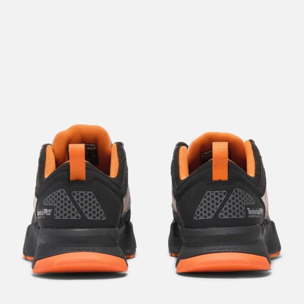 A look at the heels of a pair of Timberland PRO Powertrain composite toe men's athletic work sneakers in black and orange with a blank background.