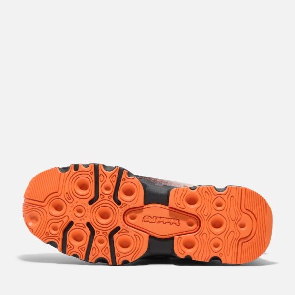 The sole of the right boot on a Timberland PRO Powertrain composite toe men's athletic work sneakers in black and orange with a blank background.