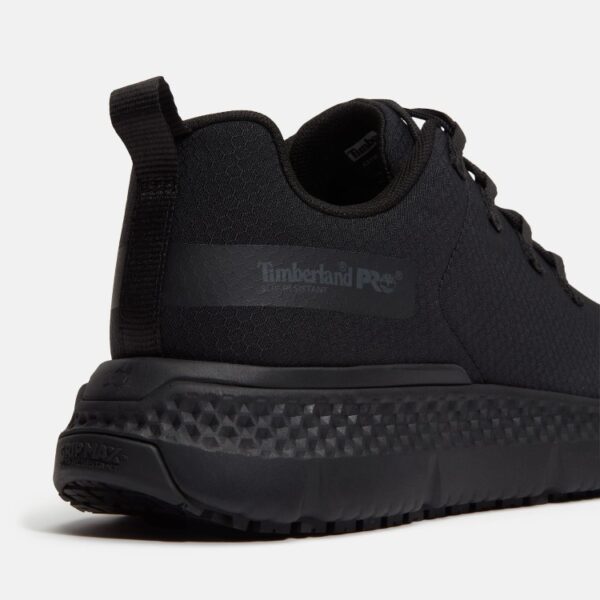 Close up of Timberland Power Shift soft toe women's hospitality work sneaker in black showing slip-resistant stamp and with a blank background.
