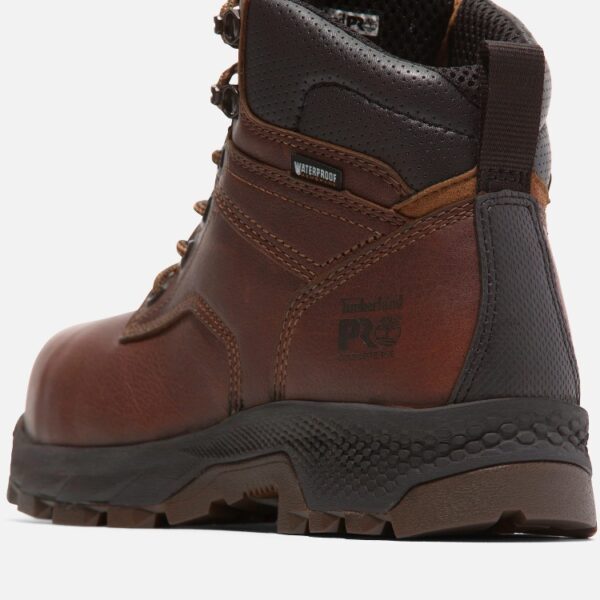 Close up of Timberland TiTAN EV safety toe women's 6-inch work boot in brown showing composite toe stamp and waterproof tag with a blank background.